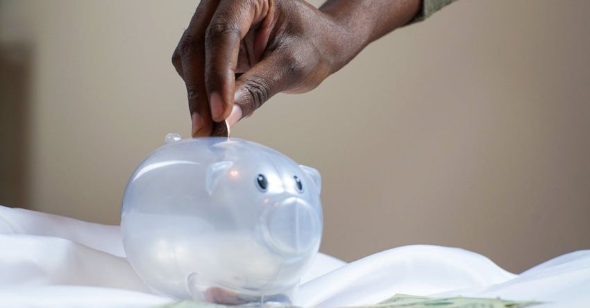 Savings - Person Putting Coin in a Piggy Bank