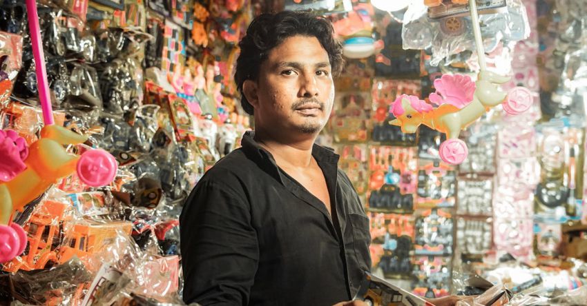 Bargains - A man standing in a store with a lot of toys