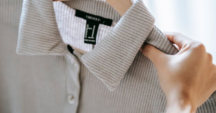 Discounts - Crop anonymous female designer holding wooden hanger with elegant shirt while preparing for fashion event